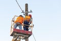 Electricians on the pillars install the mount for the power line. Professional electricians work on the tower