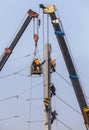 Electricians repairing wire on electricity power pole with hydraulic platform.