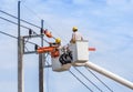 Electricians repairing wire of the power line with bucket hydraulic lifting platform Royalty Free Stock Photo