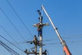 Electricians repairing wire of the power line on electric power pole with crane