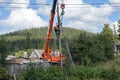 Electricians sits on the pole and secures him with chains to the crane boom for further disassembly.