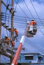 Electricians team with crane truck are working to install electrical systems on power poles against blue sky