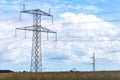 Electricity concept. High voltage power line pylons, electrical tower on a green field with blue sky. Royalty Free Stock Photo