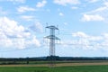 Electricity concept. High voltage power line pylons, electrical tower on a green field with blue sky. Royalty Free Stock Photo