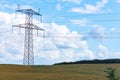 Electricity concept. High voltage power line pylons, electrical tower on a green field with blue sky. Royalty Free Stock Photo