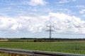 Electricity concept. High voltage power line pylons, electrical tower on a green field with blue sky. Royalty Free Stock Photo