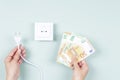 Electricity cost and expensive energy concept. Female hands holding electric power plug and Euro money banknotes near Royalty Free Stock Photo