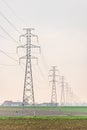 Electricity distribution system. High voltage overhead power line, power pylon, steel lattice tower standing in the field. Royalty Free Stock Photo