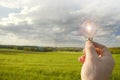 Electricity and green energy.Light bulb in hand on electricity power line background. Power lines on blue sky and green Royalty Free Stock Photo