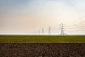 electricity pole with high tension power transmission cable in green fields Royalty Free Stock Photo