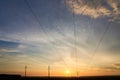Electricity poles and electric power transmission lines against vibrant blue sky at sunset on a hot day. High Voltage towers Royalty Free Stock Photo