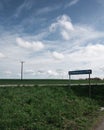 Electricity poles on green famlands next to a rural road and a street sign with the name of the nearby lake SvaneholmssjÃÂ¶n on a