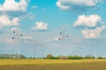 Electricity poles with overhead electrical wires through cultivated field Royalty Free Stock Photo
