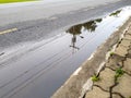 Electricity post and line reflect on the water-logged on the street.