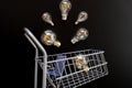 electricity price.Electric lamps and in a shopping cart on black board background.Rising electricity cost. Energy crisis Royalty Free Stock Photo