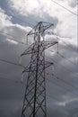 An electricity pylon against a dark cloudy sky. Sunlit insulators. Royalty Free Stock Photo