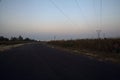 Electricity pylon in a field behind an embankment at the edge of a country road at sunset Royalty Free Stock Photo