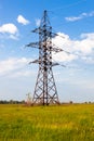 Electricity pylon on the green grass against the cloudy sky Royalty Free Stock Photo