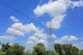 Electricity pylon of high-voltage power lines on green field with beautiful clouds on blue sky Royalty Free Stock Photo