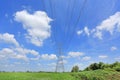 Electricity pylon of high-voltage power lines on green field with beautiful clouds on blue sky. Perspective and Landscape view