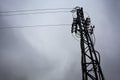 Electricity pylon with over head cables passing on it and a cloudy sky as background Royalty Free Stock Photo