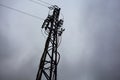 Electricity pylon with over head cables passing on it and a cloudy sky as background Royalty Free Stock Photo