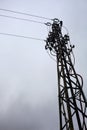 Electricity pylon with over head cables passing on it and a cloudy sky as background Royalty Free Stock Photo