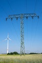 Electricity pylon, overhead power lines and a wind turbine Royalty Free Stock Photo