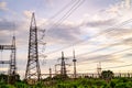 Electricity pylons against orange and yellow sunset. Selective focus. Royalty Free Stock Photo