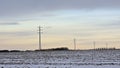 Electricity pylons along snow covered farm land under a colorful evening sky in the flemish countryside Royalty Free Stock Photo