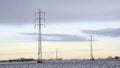 Electricity pylons along snow covered farm land under a colorful evening sky in the flemish countryside Royalty Free Stock Photo