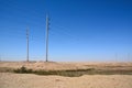 Electricity pylons in the desert in perspective against a blue sky