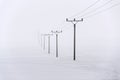 Electricity pylons from distribution power station disappearing in deep fog, winter freezing weather Royalty Free Stock Photo