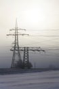 Electricity pylons from distribution power station in foggy winter freeze Royalty Free Stock Photo