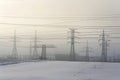 Electricity pylons from distribution power station in foggy winter freeze Royalty Free Stock Photo