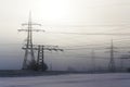 Electricity pylons from distribution power station in foggy winter freeze Royalty Free Stock Photo