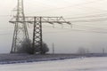 Electricity pylons from distribution power station in foggy winter freeze Royalty Free Stock Photo