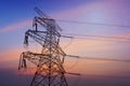 Electricity pylons, power lines and trees silhouetted against a cloudy sky