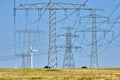 Electricity pylons and power lines with wind turbines Royalty Free Stock Photo