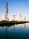 Electricity pylons reflecting in still water