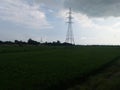 Electricity tower in green field on cloudy weather Royalty Free Stock Photo
