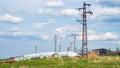 Electricity tower line power grid in countryside meadow hay heap Royalty Free Stock Photo