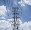 Electricity transmission lines and pylon silhouetted against blue sky and cloud,high voltage tower Royalty Free Stock Photo