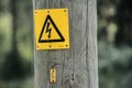 Electricity warning sign on old wooden pole. Royalty Free Stock Photo