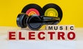 ELECTRO MUSIC inscription on wooden cubes on the background of vinyl records and headphones. Musical concept