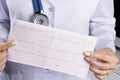 Electrocardiogram, ecg in hand of a female doctor. Medical health care. Clinic cardiology heart rhythm and pulse test closeup.