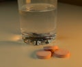 Electrolyte medication tablets beside glass of water