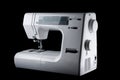 Electromechanical modern white plastic sewing machine on a black background, isolate