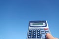Electronic calculator and the hand in the blue sky Royalty Free Stock Photo