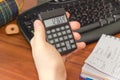 Electronic calculator in the hand of schoolboy over the desktop Royalty Free Stock Photo